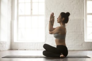 young attractive woman in gomukasana pose, white loft studio bac